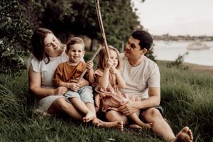 Family bonding session captured on a grassy hillside near the water.