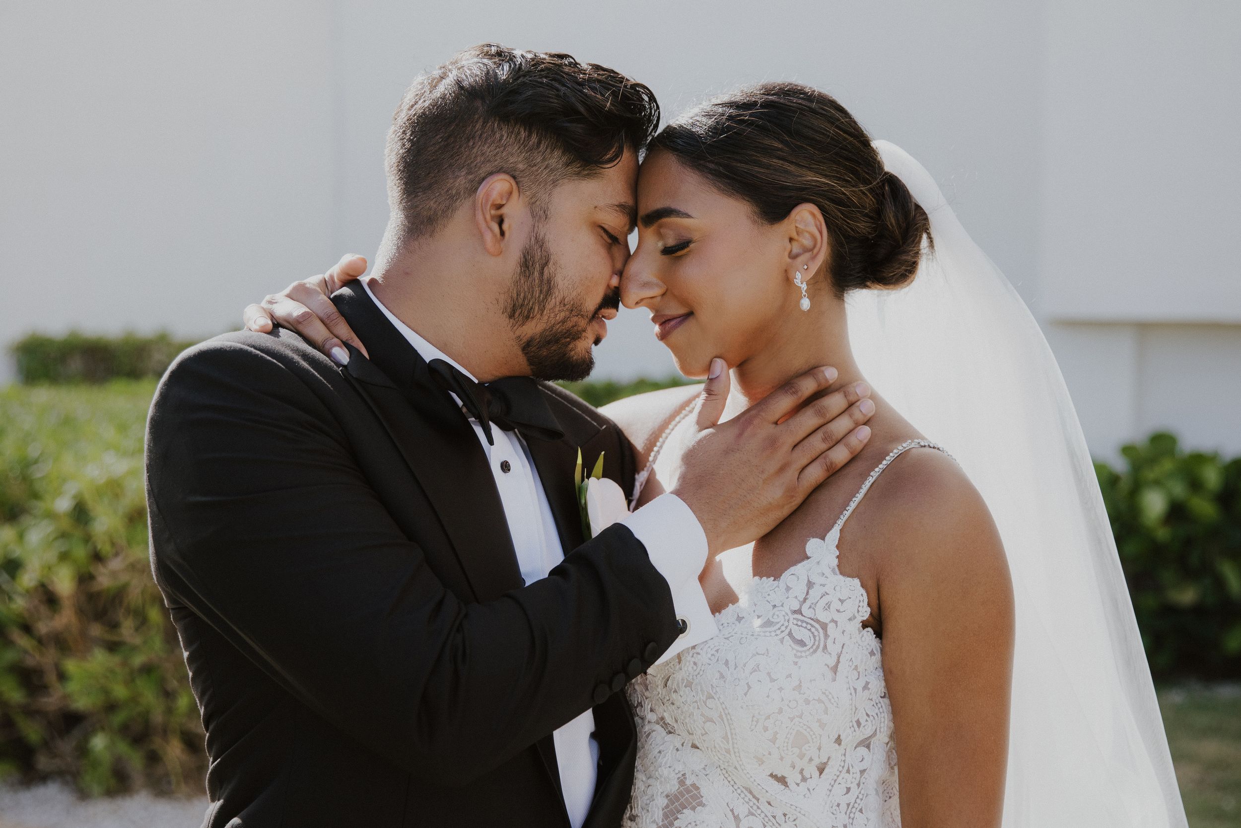 An intimate close-up of a wedding couple sharing a tender moment outdoors.