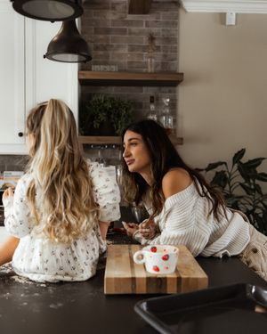 Friends enjoying conversation and laughter in modern kitchen with exposed brick and pendant lighting.