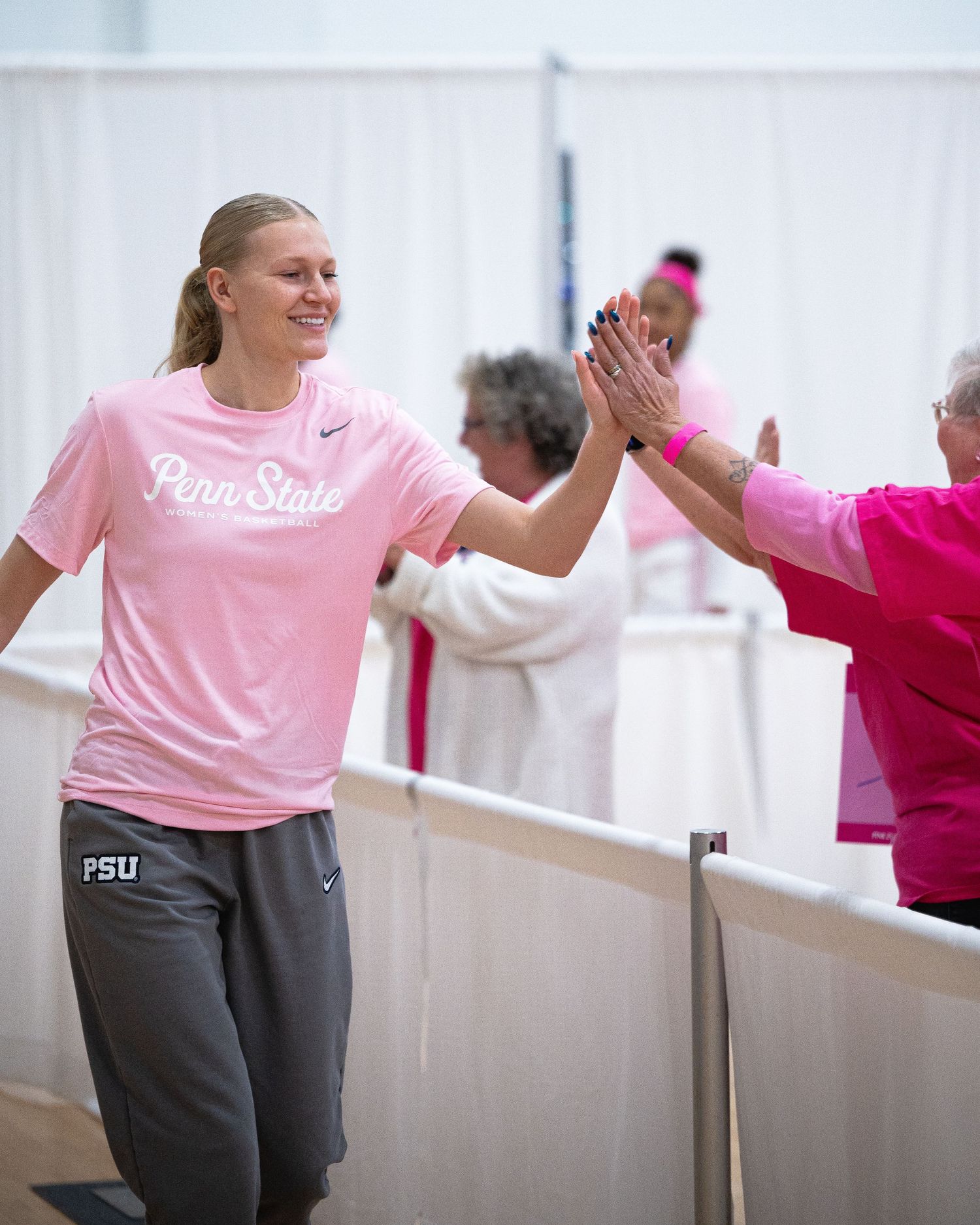 Athletes share high fives during pink-themed breast cancer awareness event at Penn State.