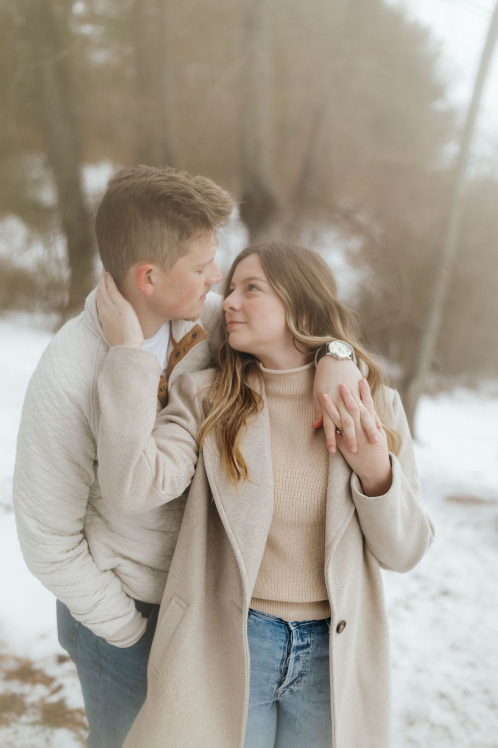 Intimate couples portrait in the snow with soft natural lighting and neutral winter attire.
