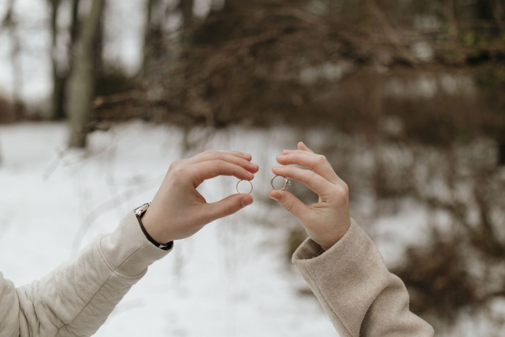 Close up of hands reaching toward each other in the snow showing an engagement moment.