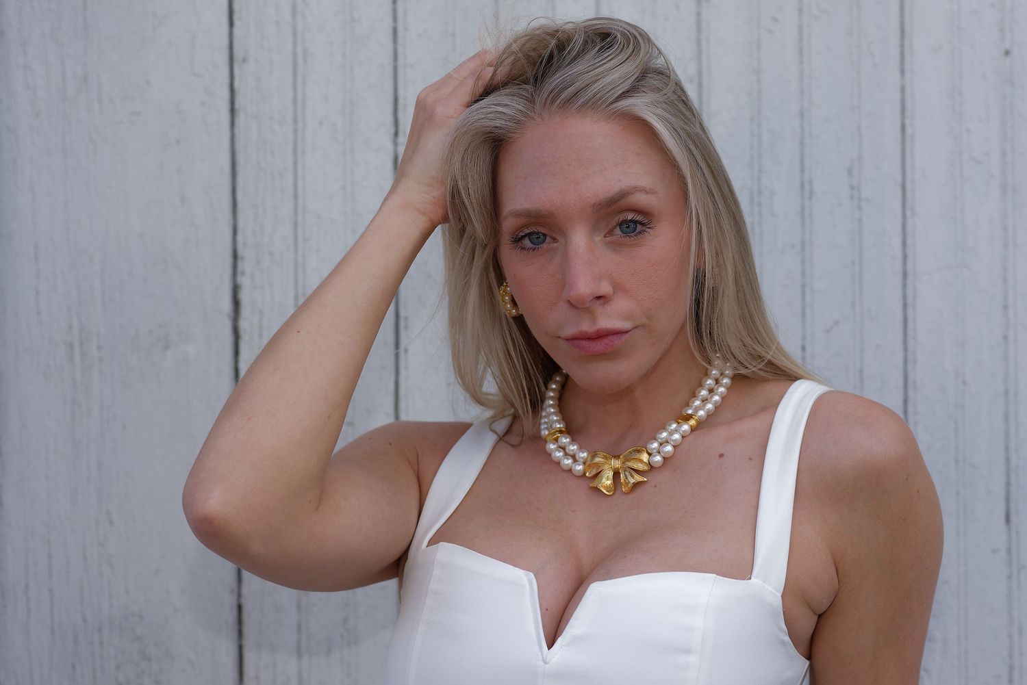 Portrait of a model in white dress against weathered wood background.