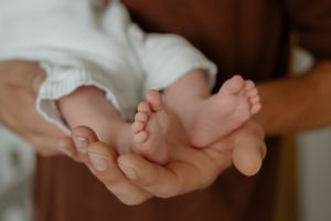 Close-up of tiny newborn feet resting in gentle hands against a light background.