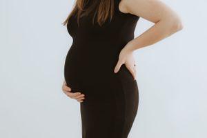 A profile view showcasing a pregnancy bump in a black form-fitting dress.