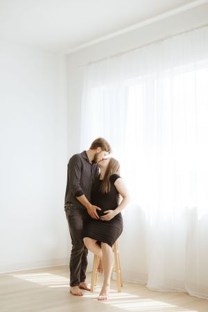 A tender moment between a couple sharing an embrace near a sunlit window.