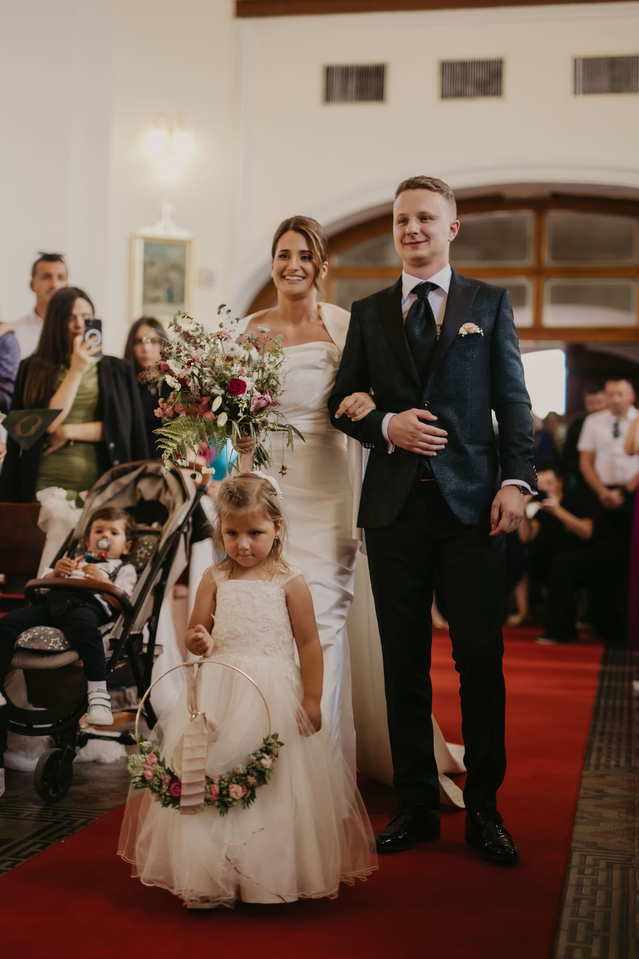 Wedding processional on red carpet with flower girl leading the way down the aisle.