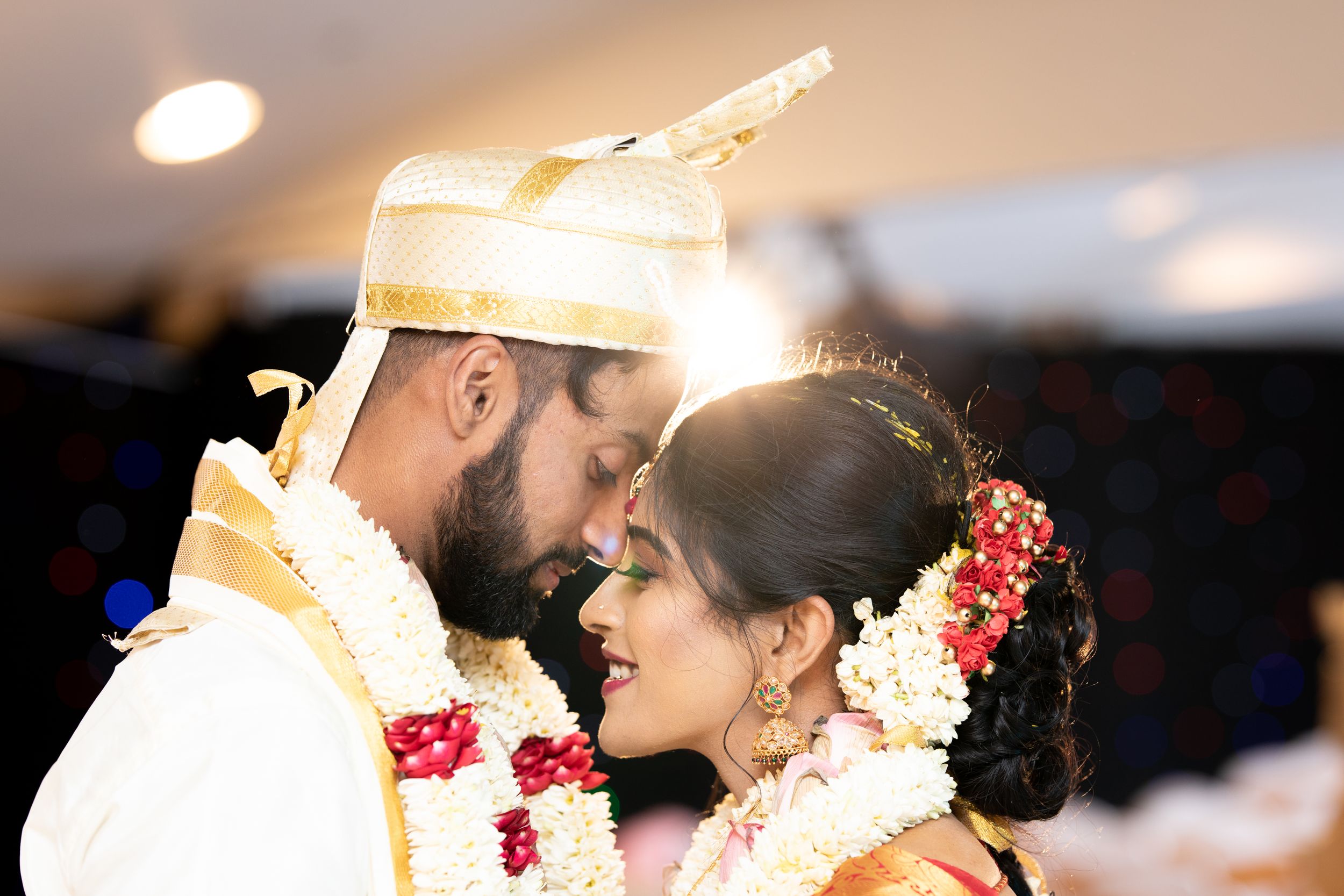 Traditional South Indian wedding couple share an intimate moment adorned in traditional attire and flower garlands.
