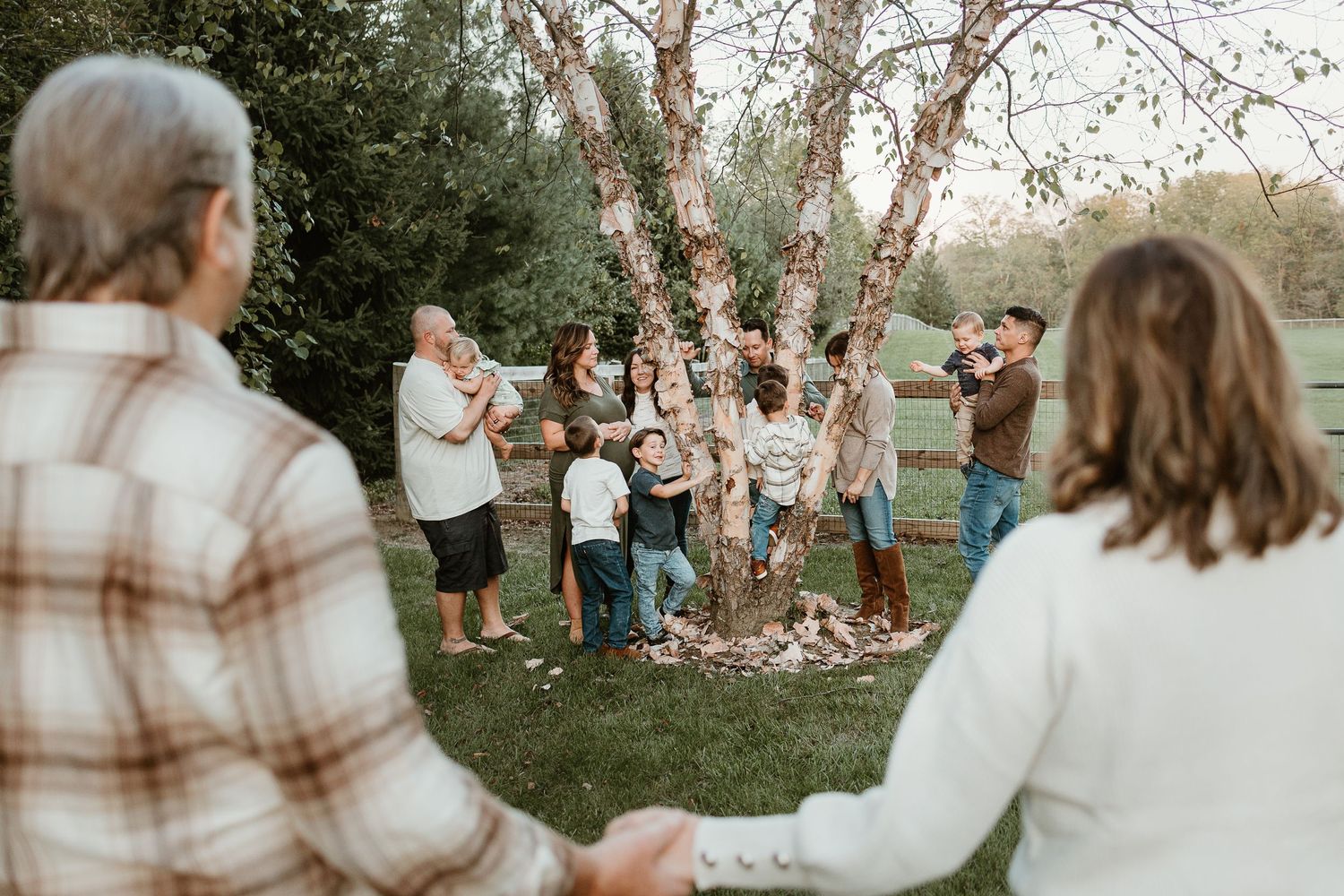 Candid outdoor family gathering with multiple groups interacting in a natural setting.