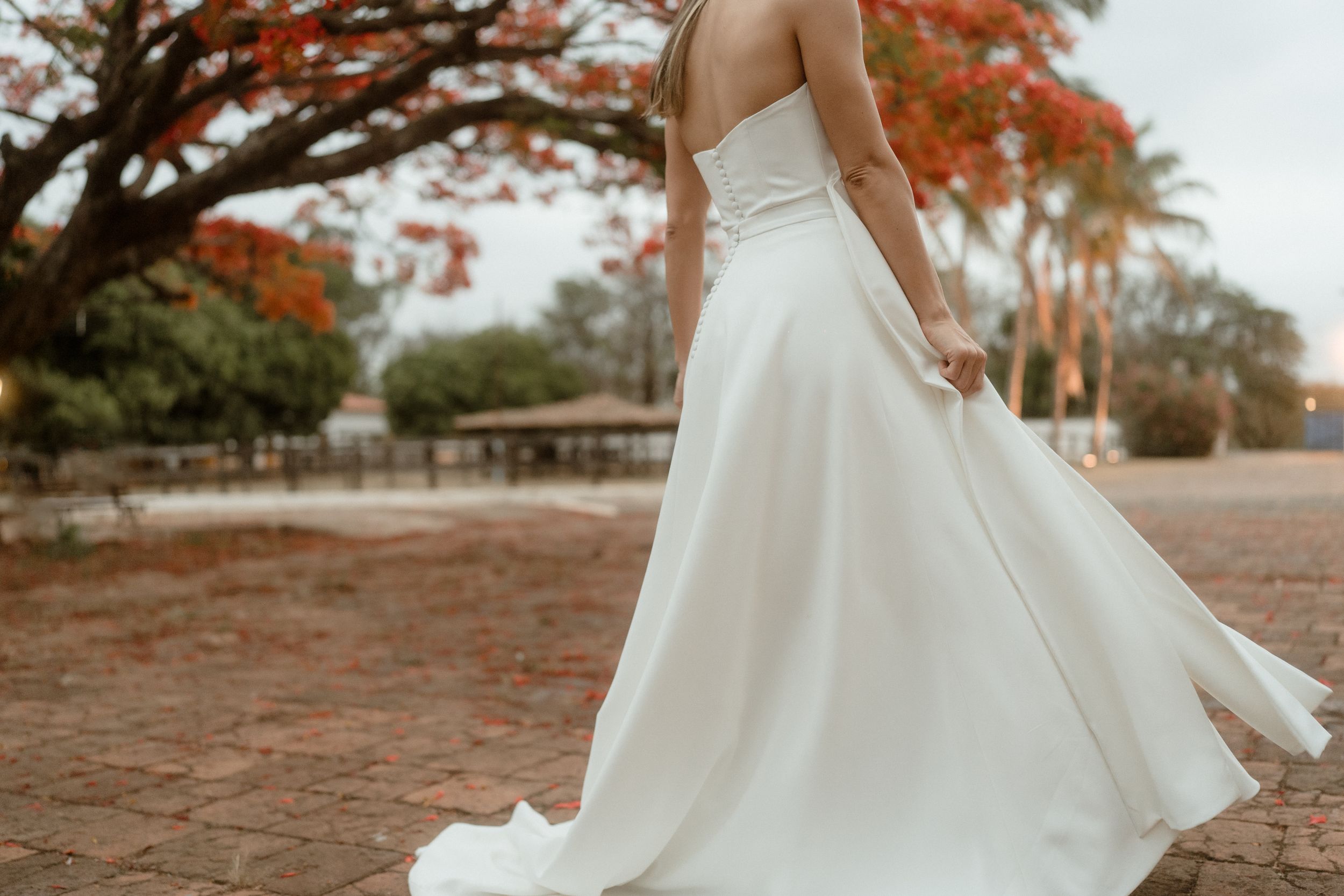 A flowing white wedding dress twirls against a backdrop of fall foliage.