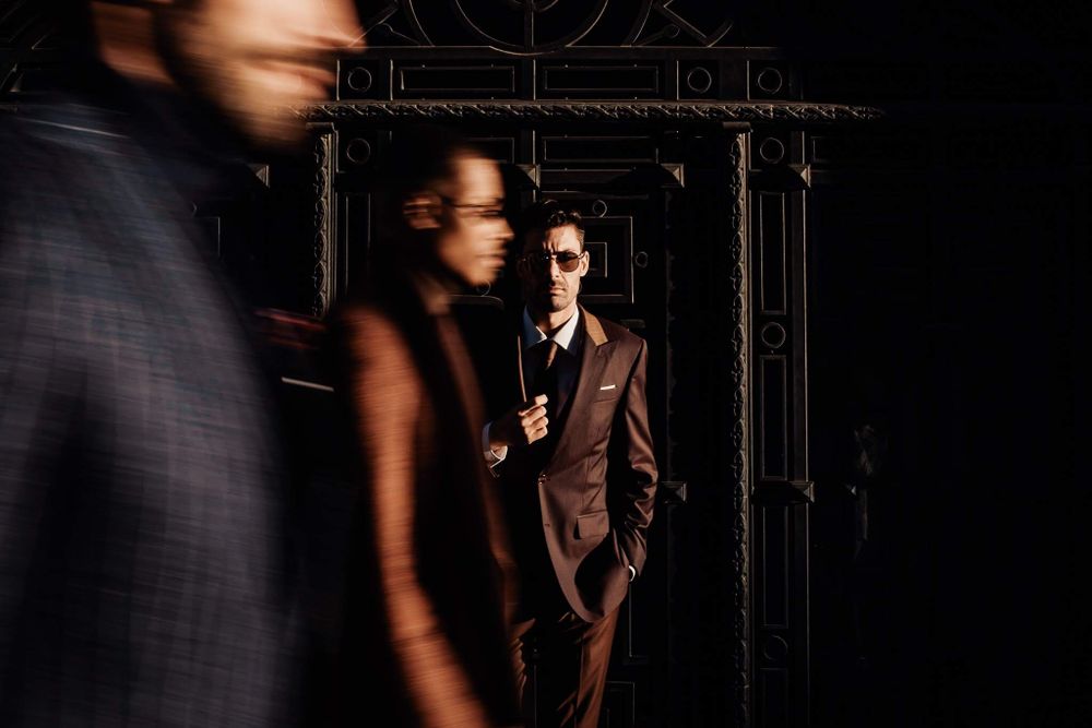 Blurred motion shot of people in formal attire standing in a dark moody environment.