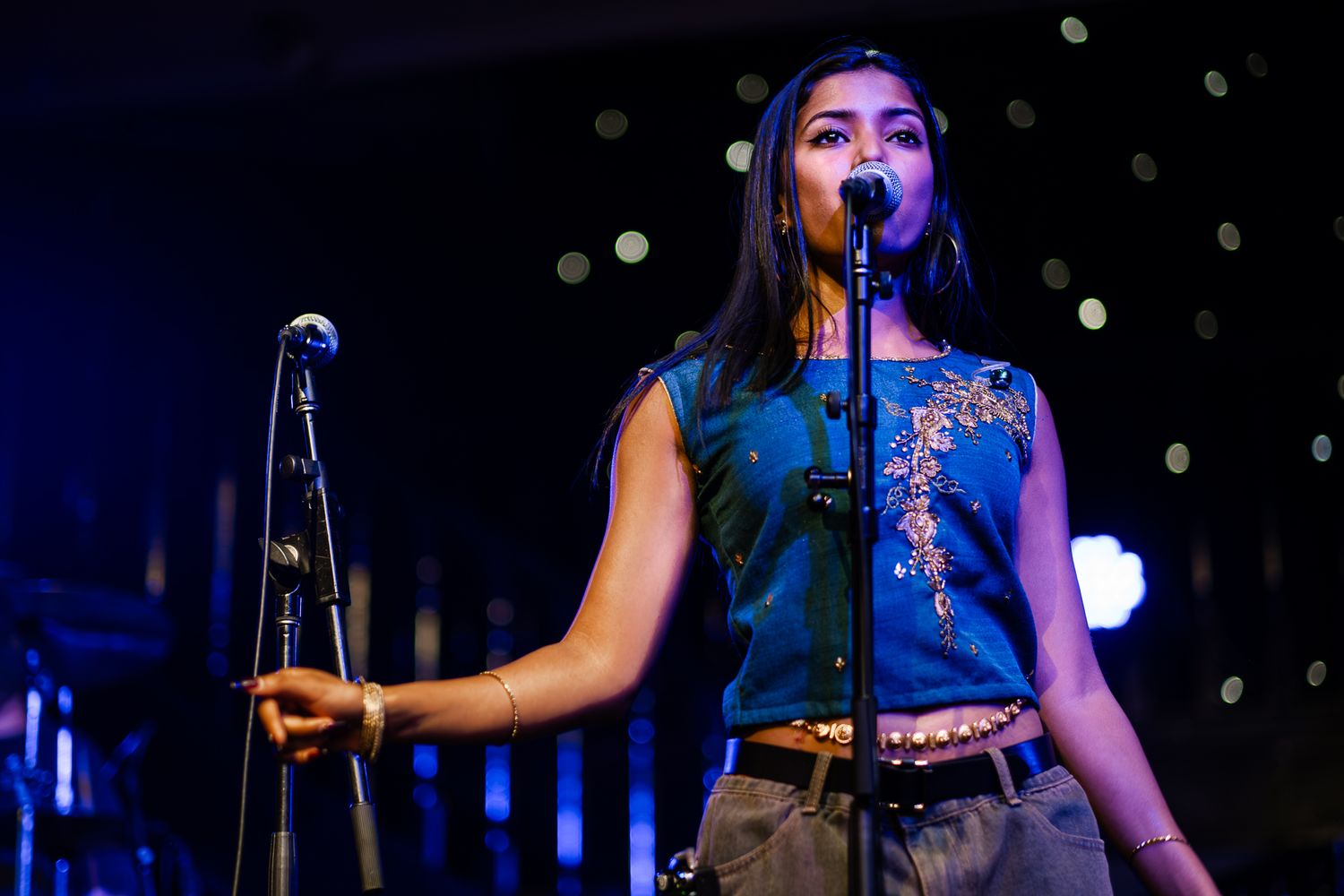 A performer in a blue tank top sings on stage during a concert performance taken by Melbourne concert photographer