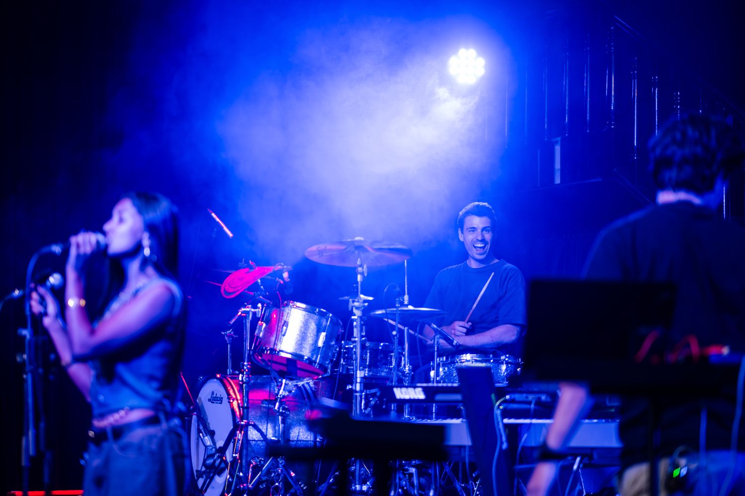 A performer in a blue tank top sings on stage during a concert performance taken by Melbourne concert photographer