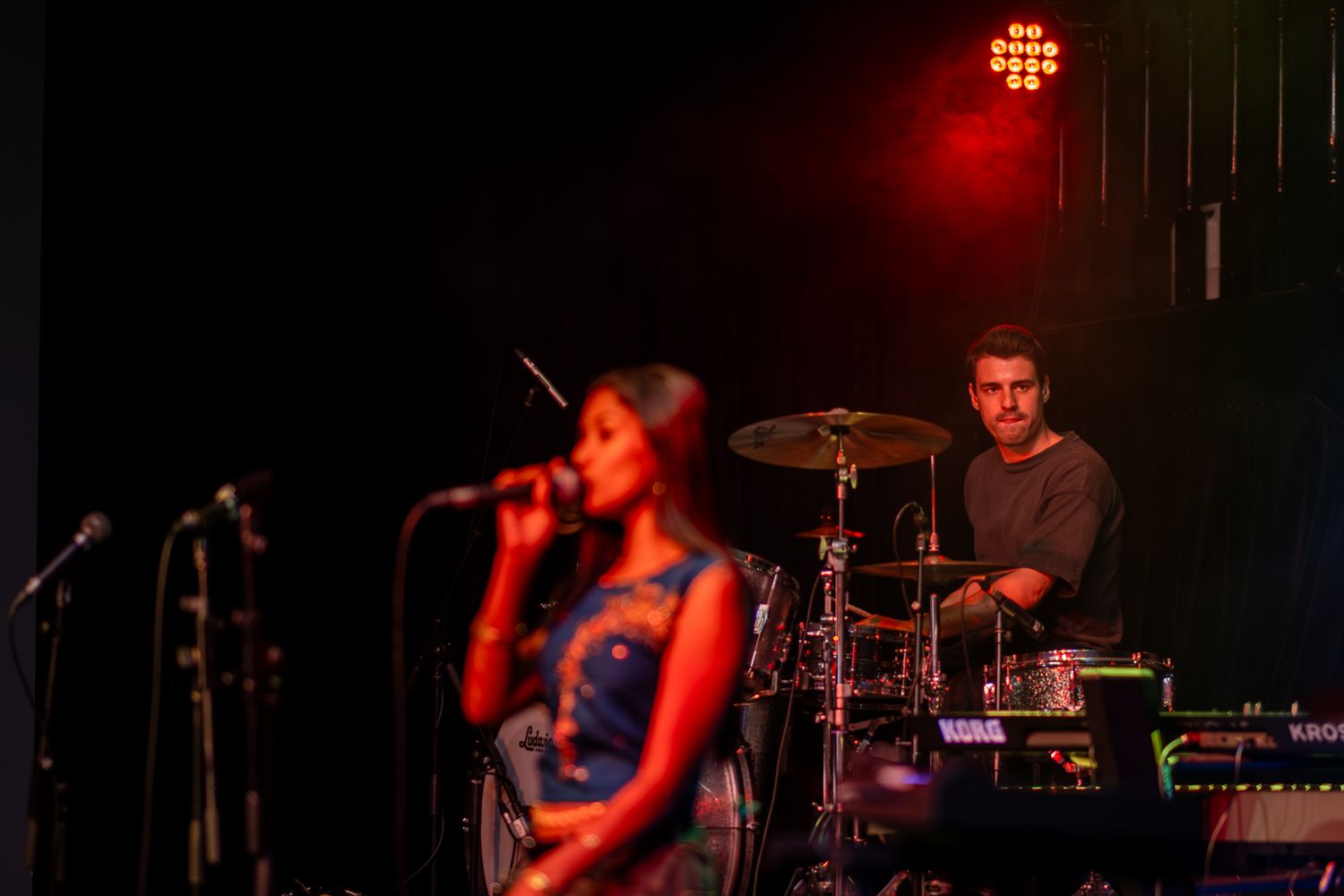 A performer in a blue tank top sings on stage during a concert performance taken by Melbourne concert photographer