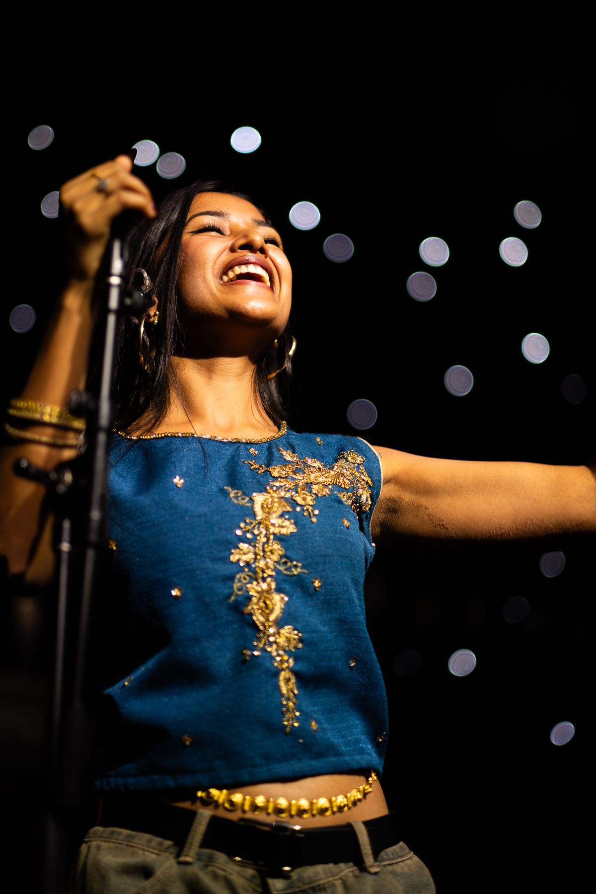 A performer in a blue tank top sings on stage during a concert performance taken by Melbourne concert photographer
