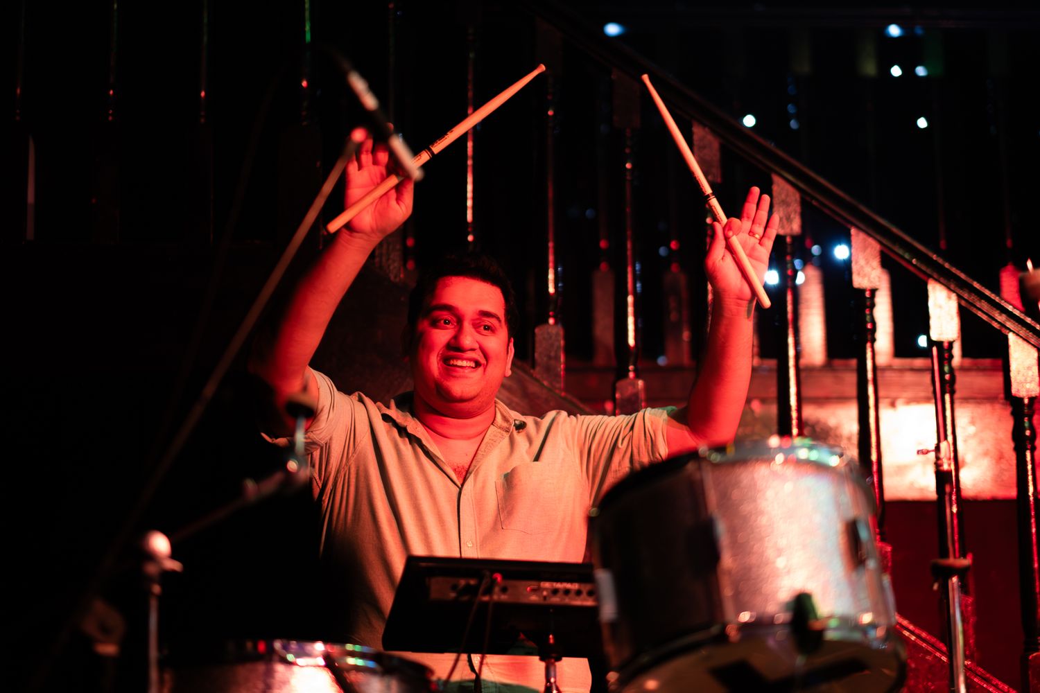 A drummer performs on stage bathed in dramatic red lighting at a live music concert taken by Melbourne concert and event photographer.