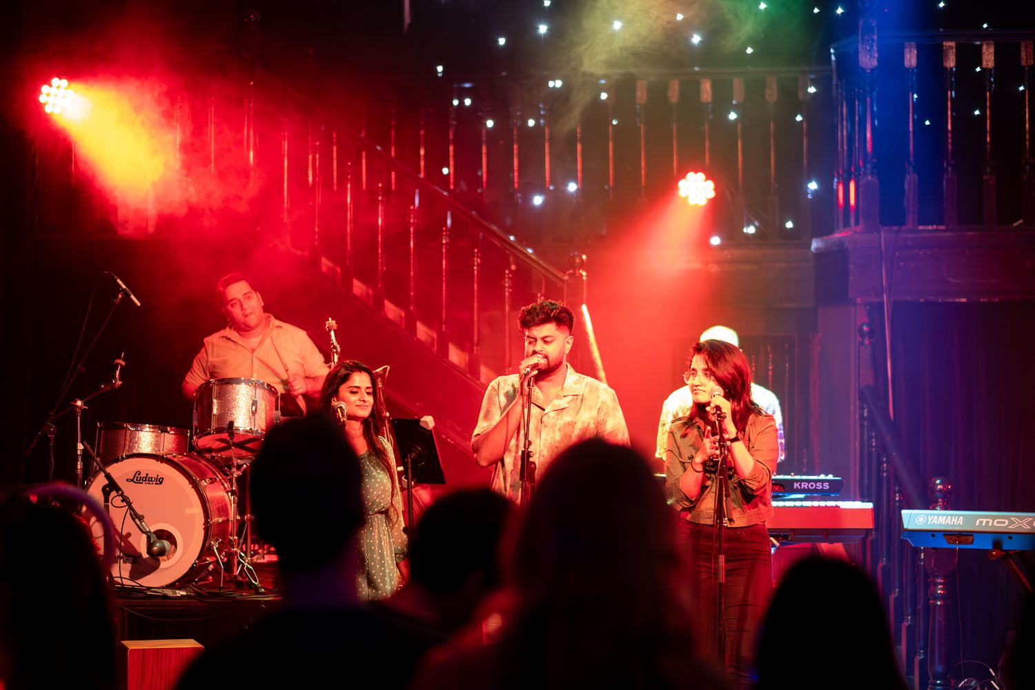 Band performs on stage with colorful rainbow lighting during evening concert taken by Melbourne concert and event photographer.