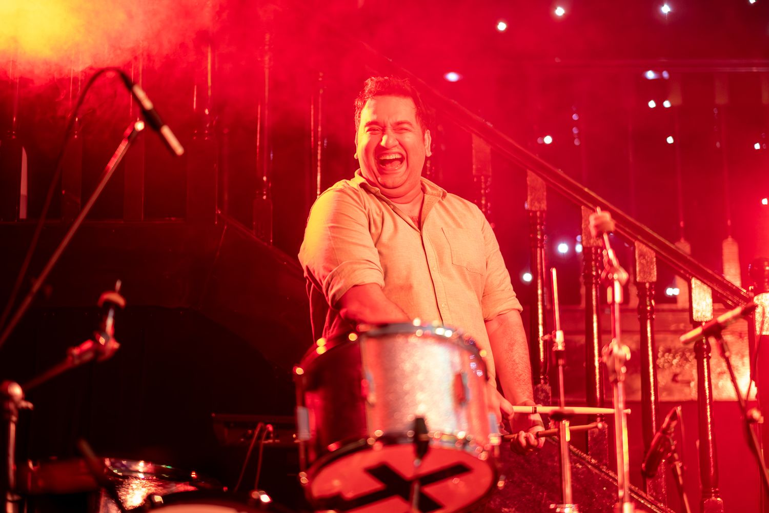 A drummer performs on stage bathed in dramatic red lighting at a live music concert taken by Melbourne concert and event photographer.