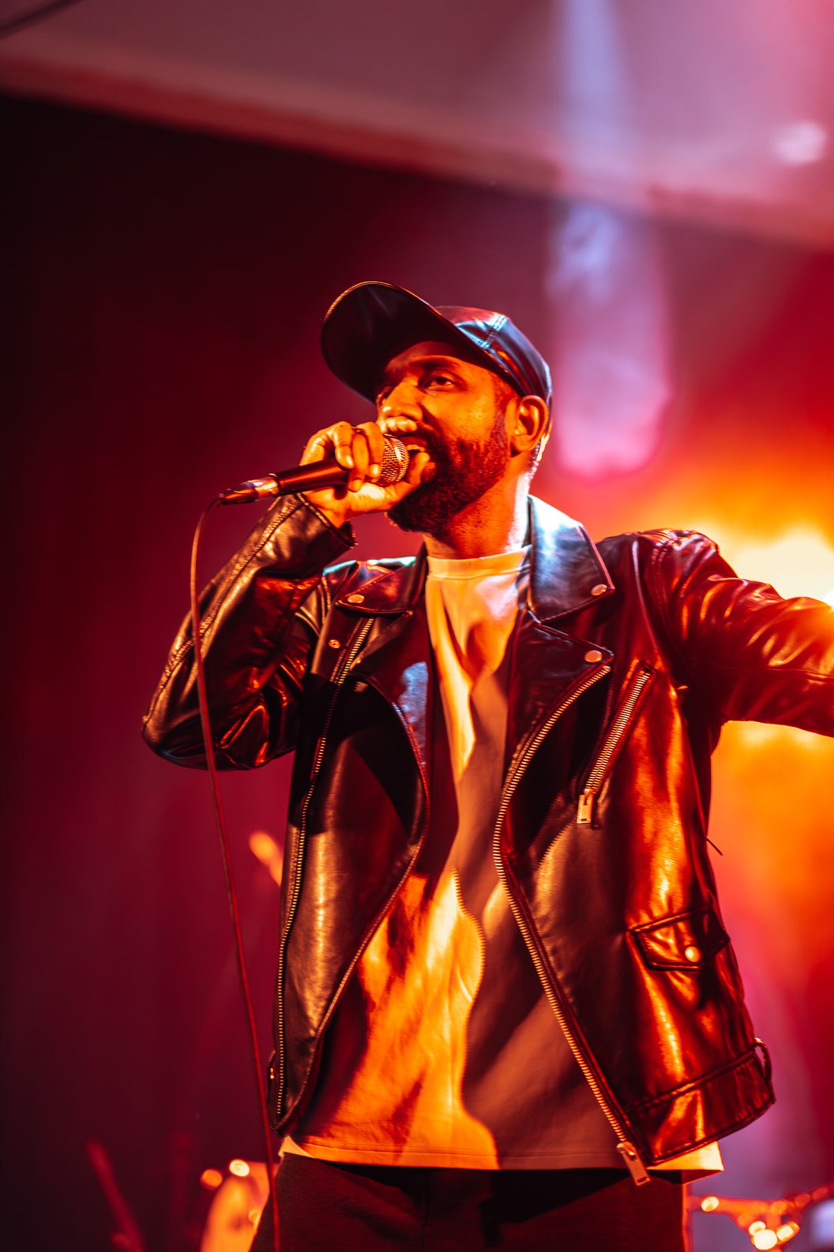 Dramatic concert performance with singer illuminated by bright orange stage lighting taken by Melbourne concert and event phorographer.