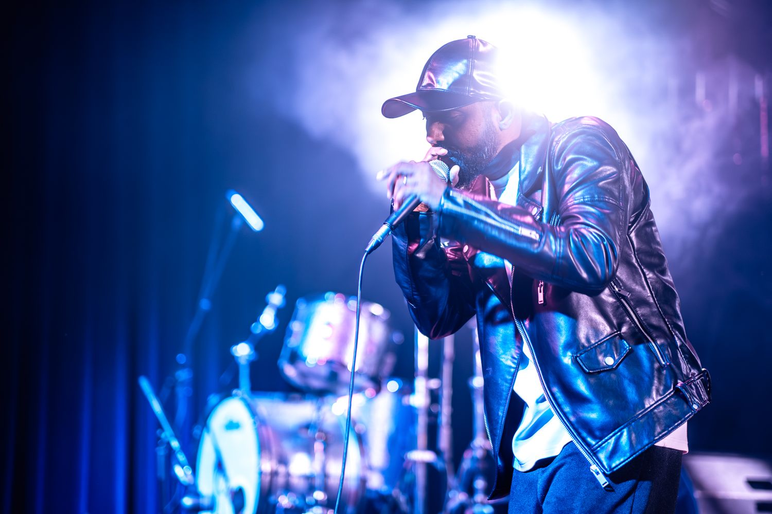 Dramatic concert performance with singer illuminated by bright blue stage lighting taken by Melbourne concert and event phorographer.