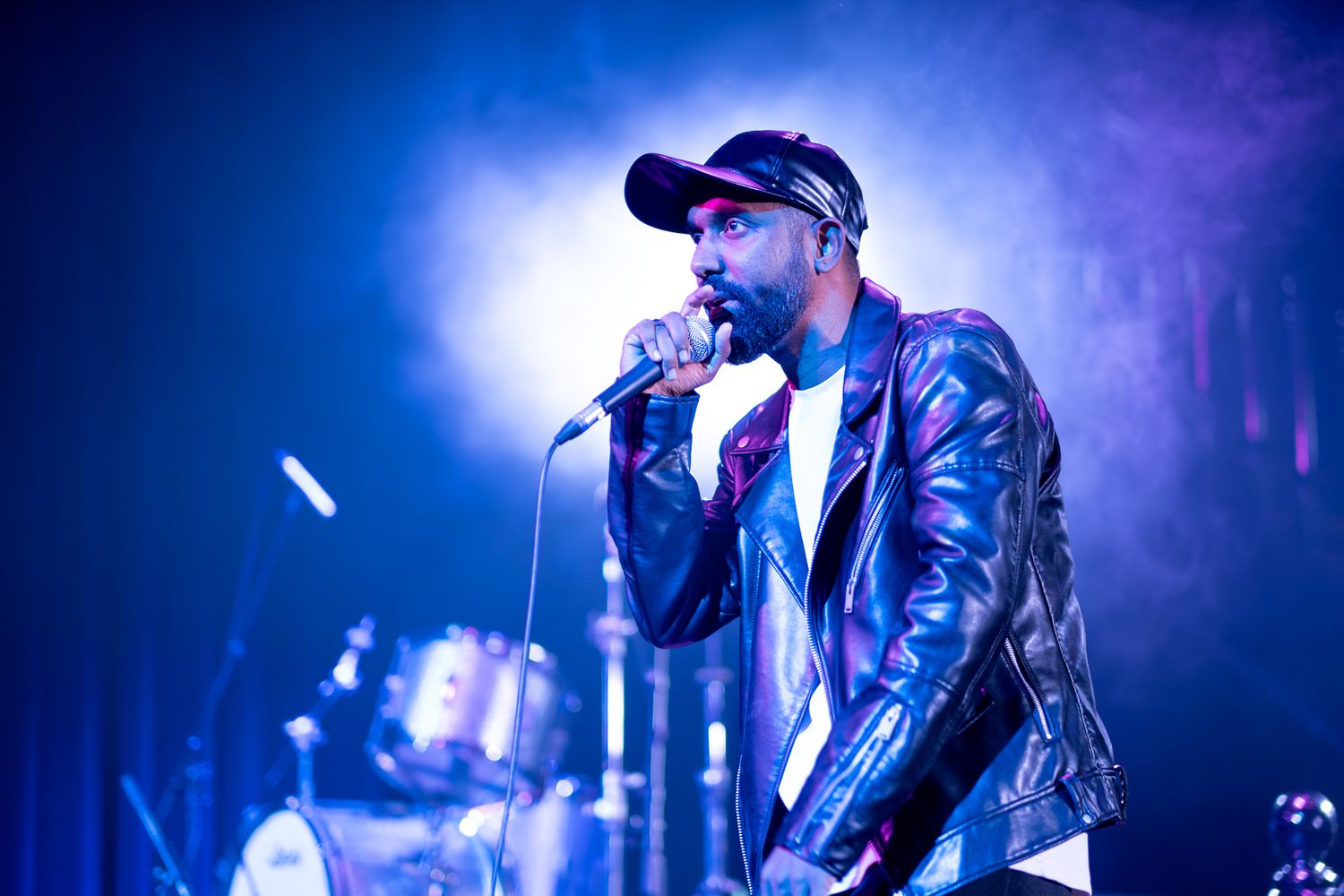 Dramatic concert performance with singer illuminated by bright blue stage lighting taken by Melbourne concert and event phorographer.