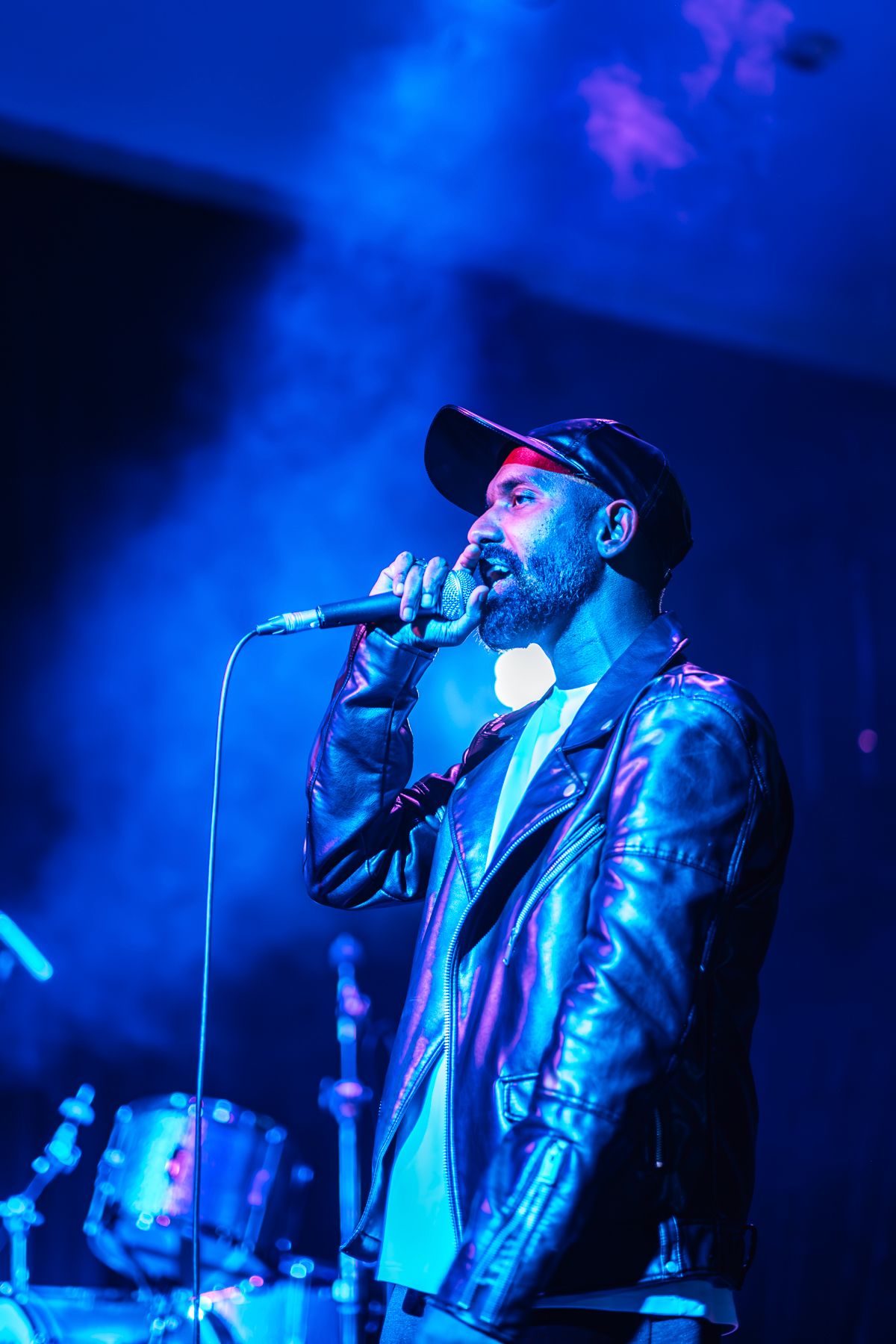 Dramatic concert performance with singer illuminated by bright blue stage lighting taken by Melbourne concert and event phorographer.