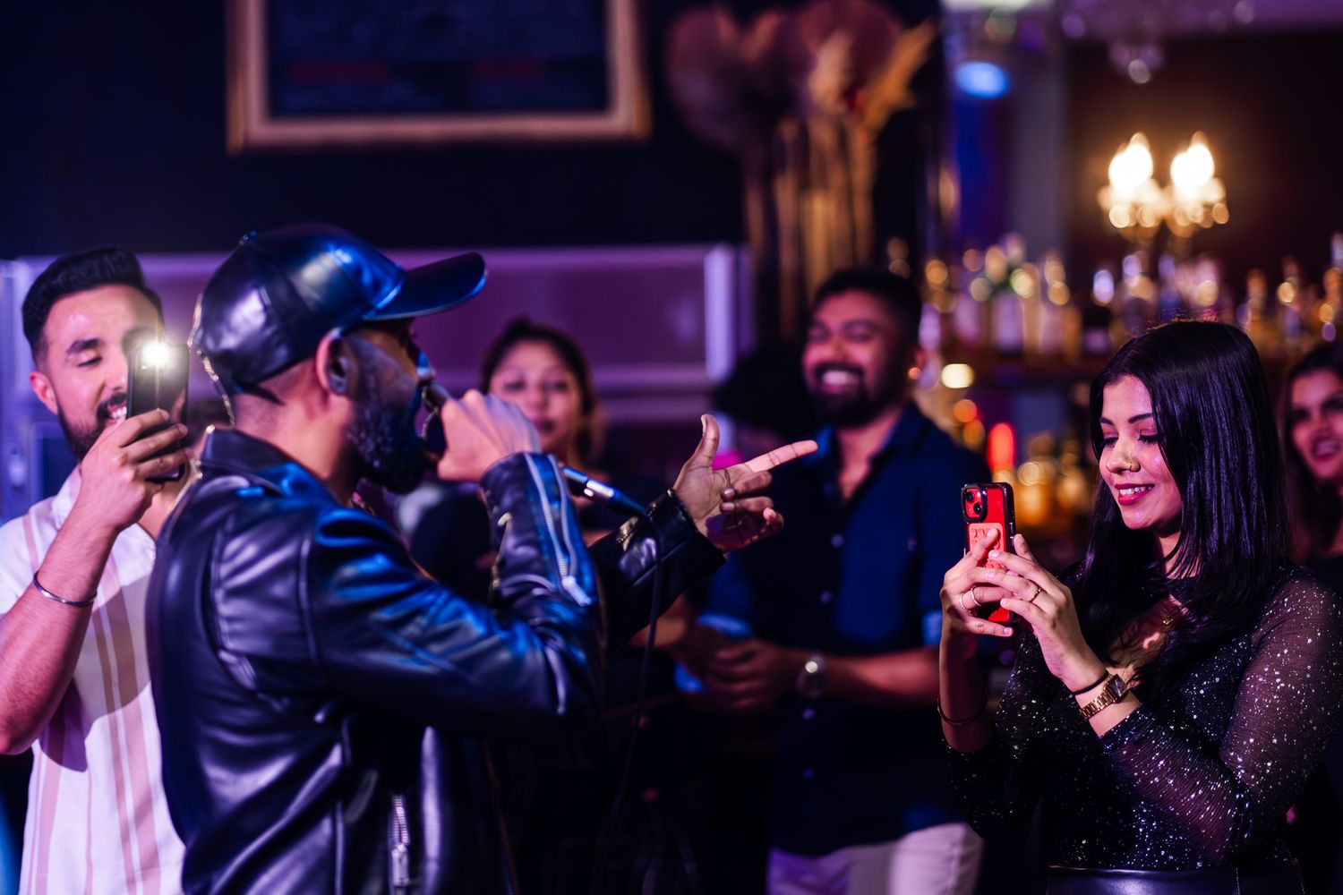 People enjoying a lively night out at a bar with drinks and animated conversation in a dimly lit atmosphere taken by Melbourne photographer