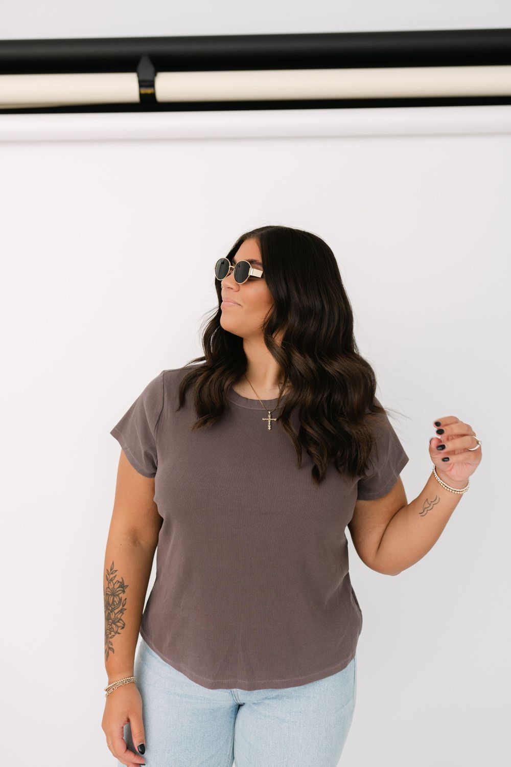 Woman in brown cropped t-shirt and blue jeans poses casually against white background in multi-angle photo set.
