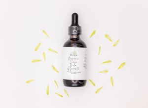 A dark glass dropper bottle with white label displayed on light background with yellow ray doodles around it.