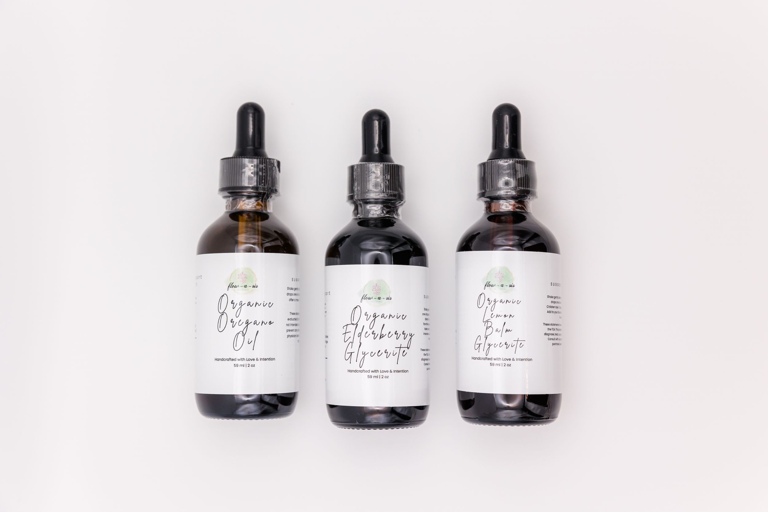 Three amber and dark glass dropper bottles with white labels arranged in a row on white background.
