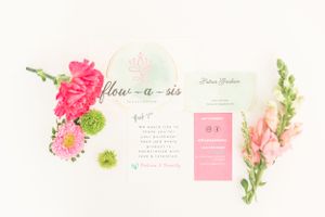 Pink wedding invitation suite with floral elements and delicate decor laid out on a white surface.