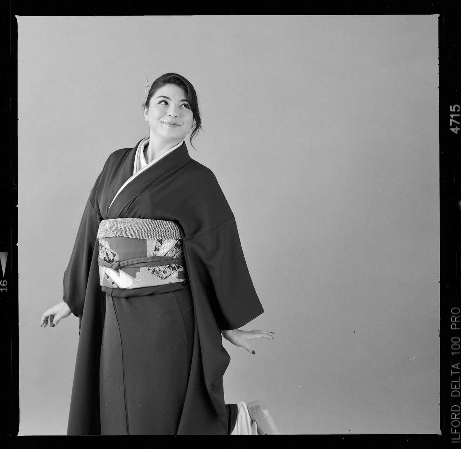 Person wearing traditional black kimono with decorative obi sash shown from multiple angles in monochrome studio photos.