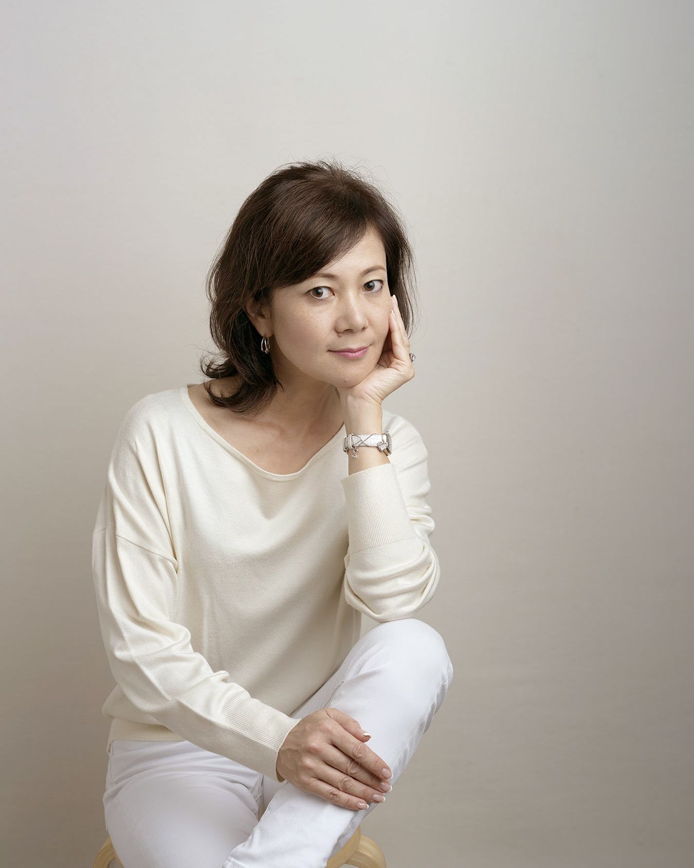 A person in a white sweater poses against a neutral background in a series of minimalist portraits.