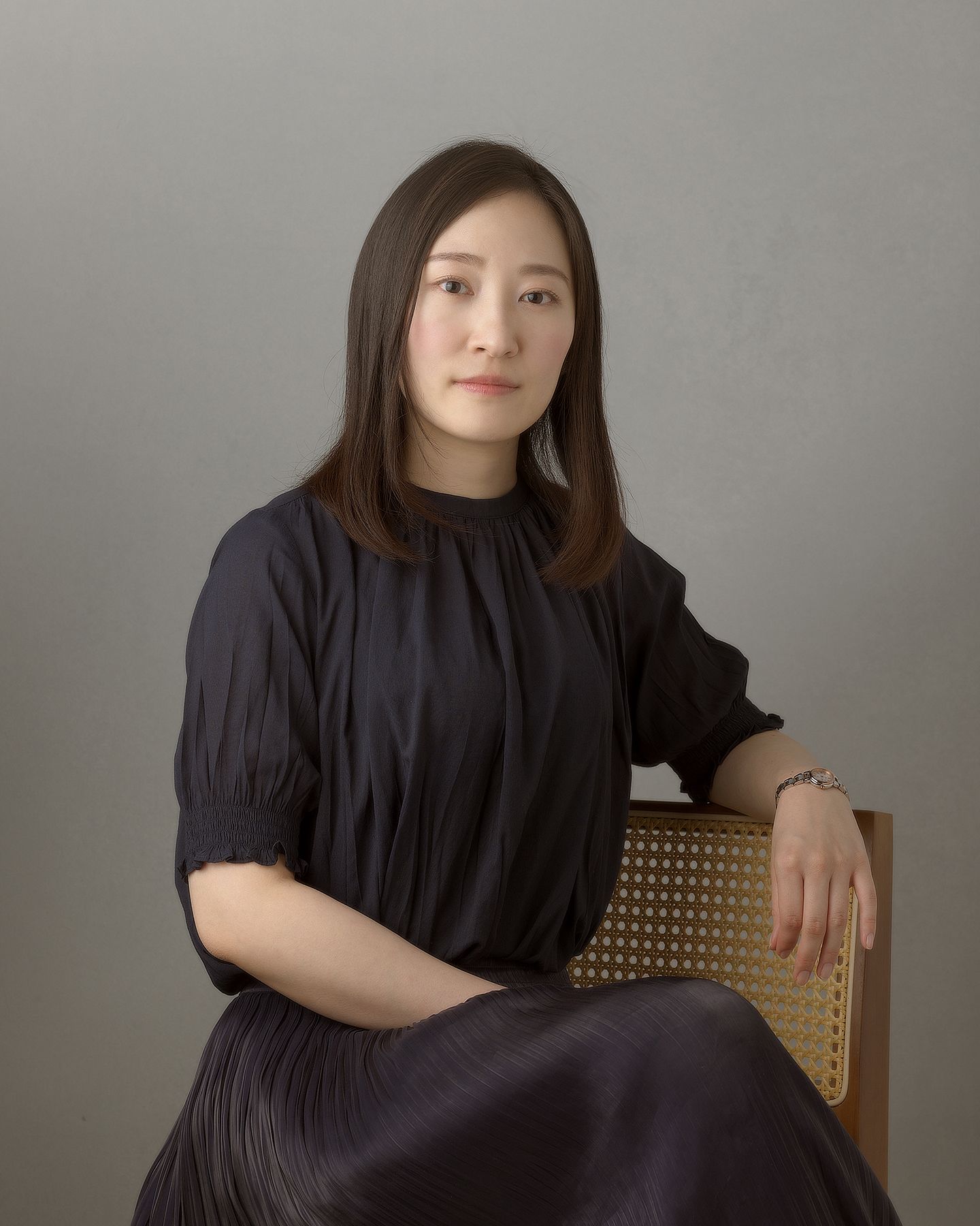 A person in a black dress poses elegantly against a neutral gray background in a series of portrait shots.