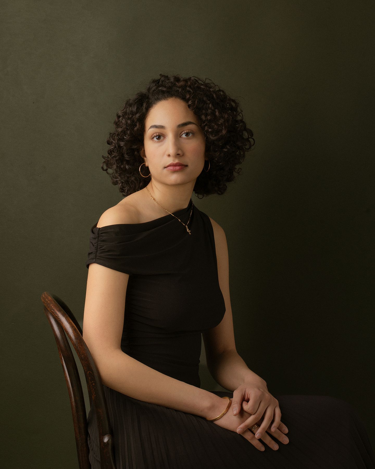 A series of moody portraits showing a woman in a black dress seated against a dark olive green background.