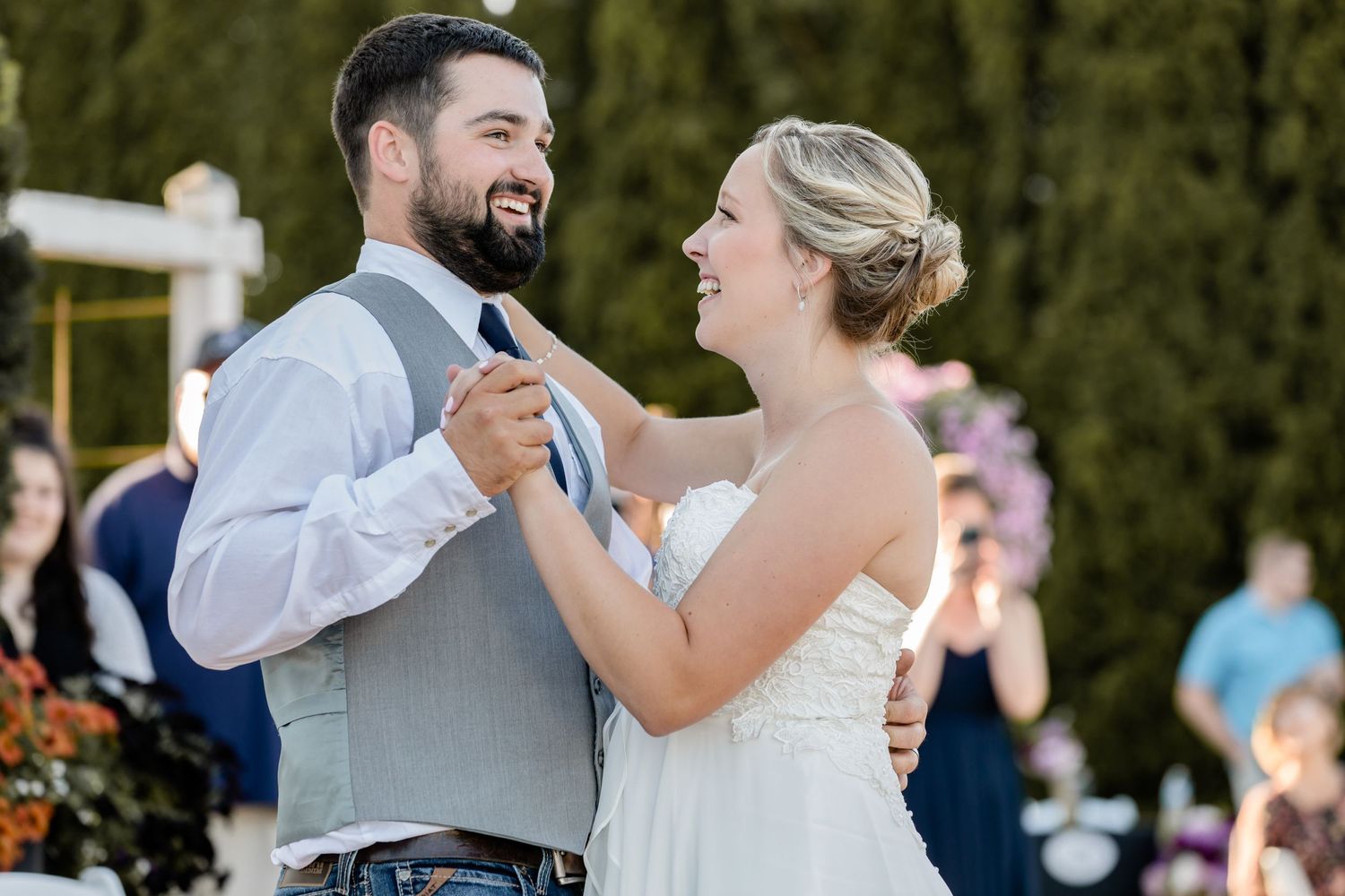 Joyful couple dancing and laughing during outdoor wedding celebration.