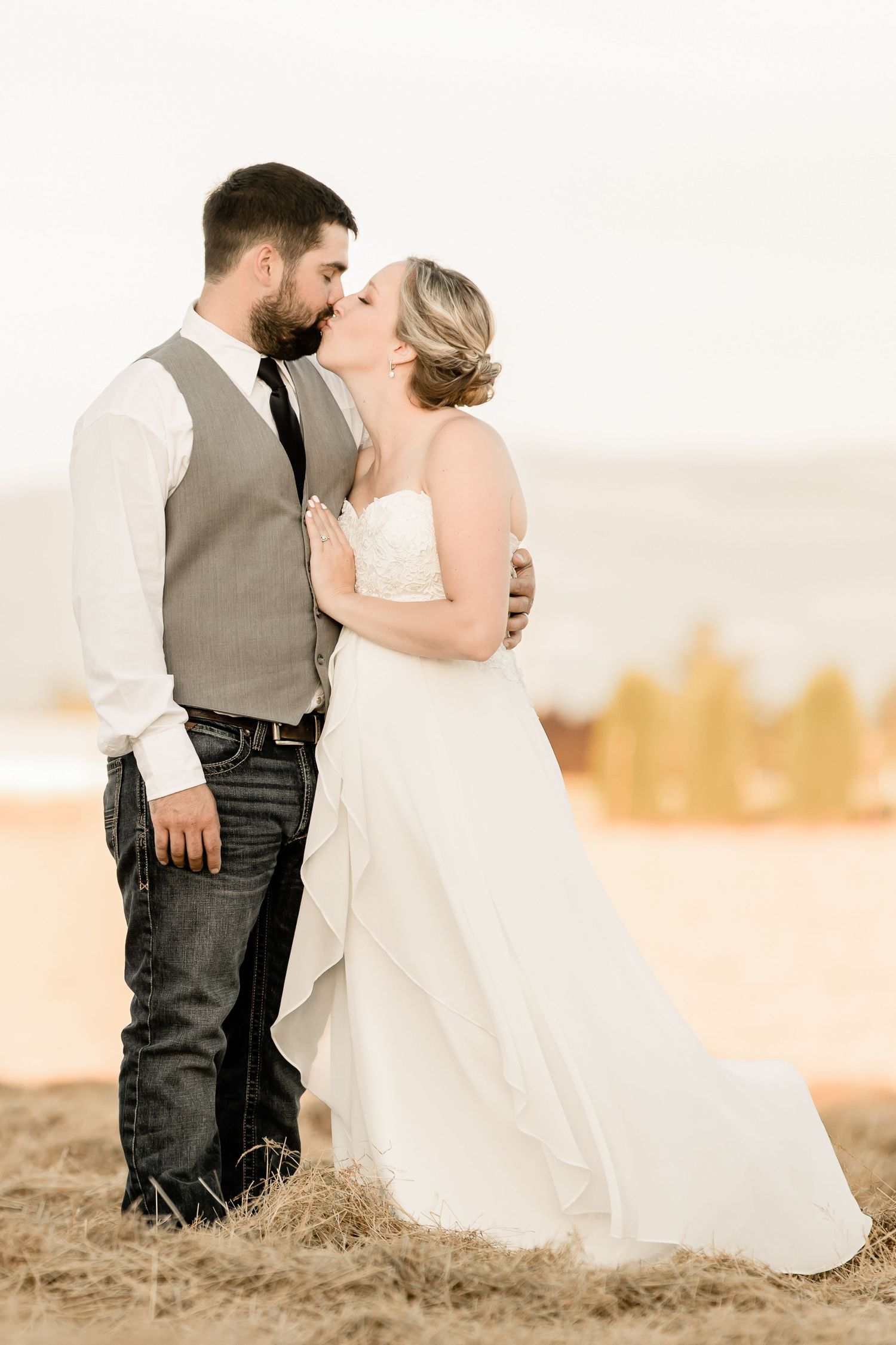 A romantic wedding portrait in soft sepia tones against a sunlit natural backdrop.