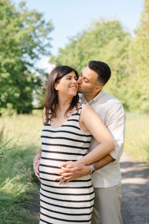 Couple sharing intimate moment in striped dress and white shirt outdoors.