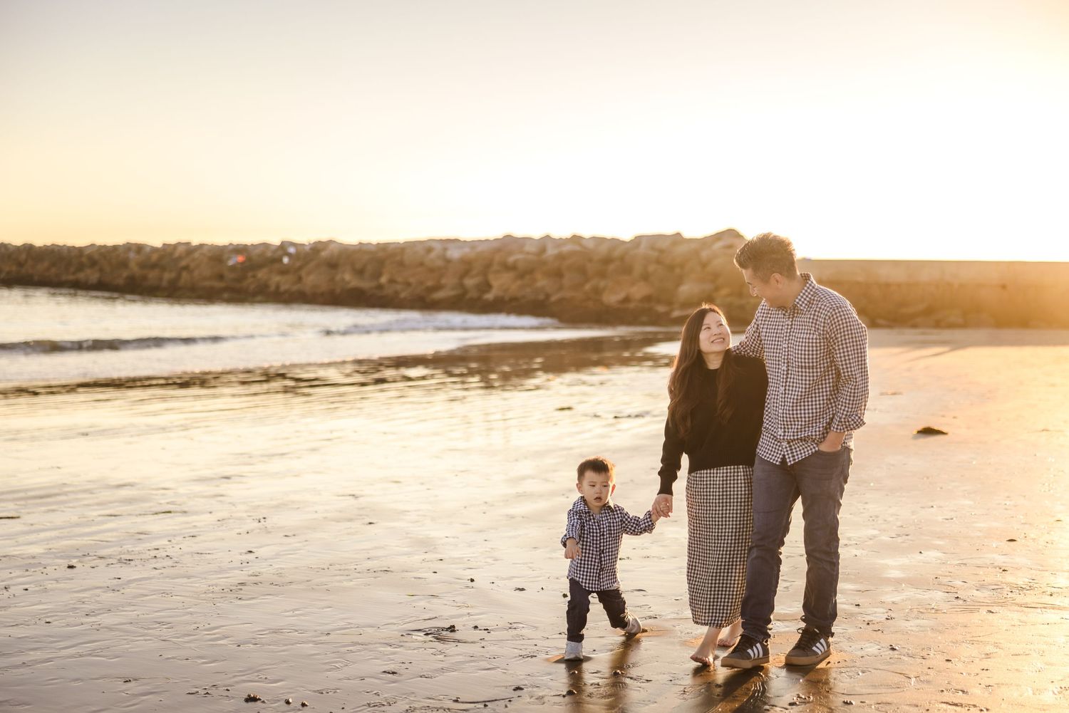 Family enjoying a sunset walk together along a scenic beach shoreline at golden hour.