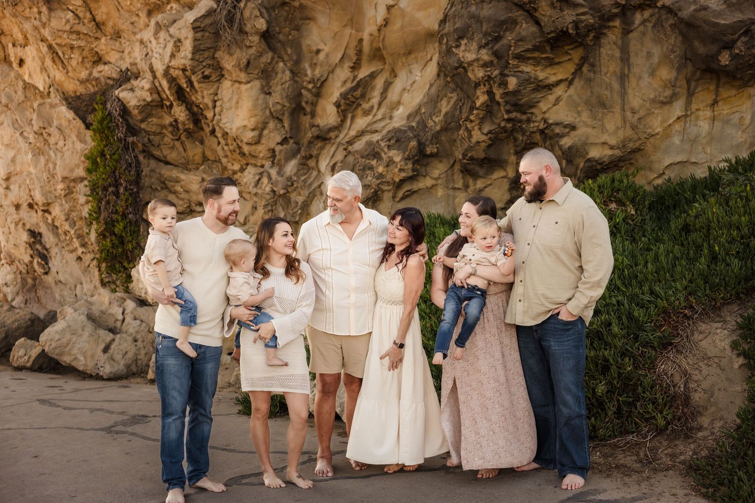 A group in coordinated neutral outfits poses together under a rocky cliff formation at sunset.
