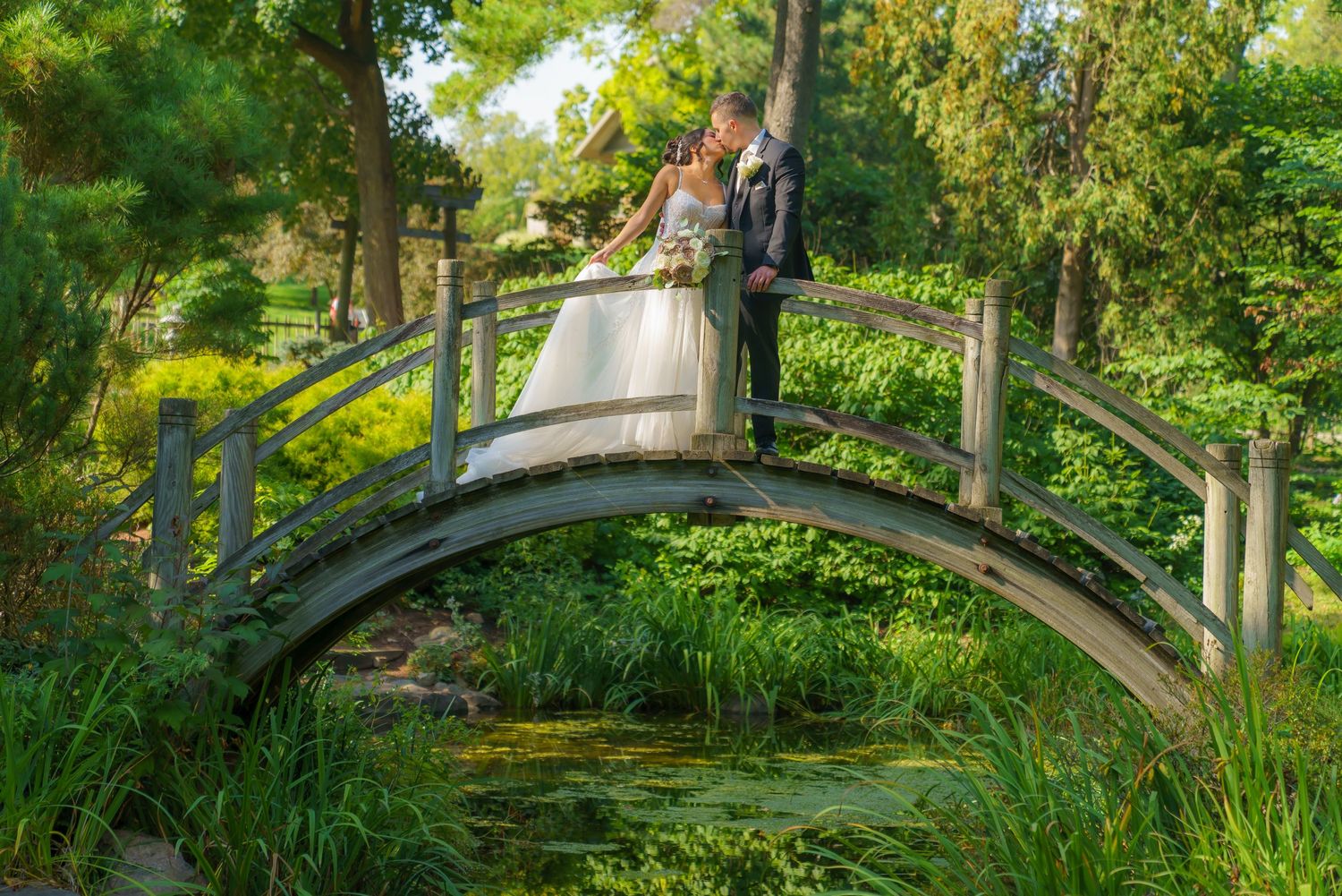 Scenic garden path with stone bridge and lush greenery in a tranquil park setting.