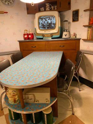 Six sequential photos show the transformation of a vintage dining table painted in aqua blue with a retro floral pattern.