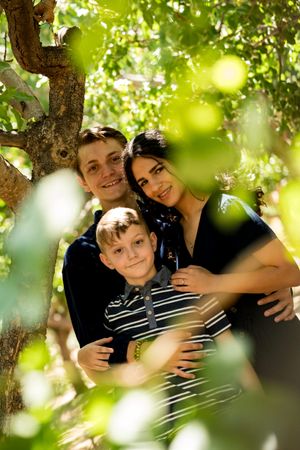 A sunlit family photo taken under a tree with bokeh effects in the foreground.