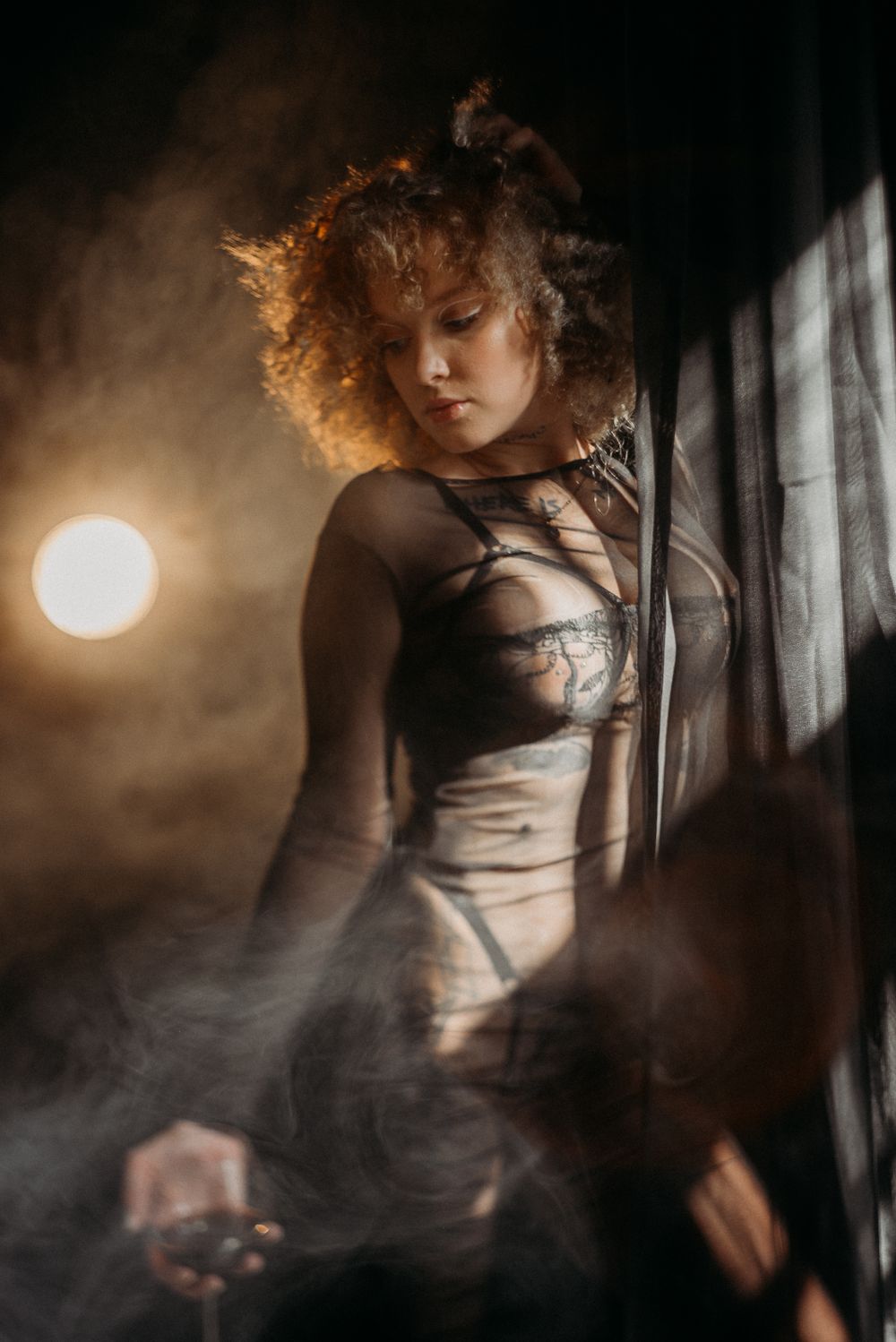 Ethereal portraits with golden lighting and misty atmosphere near curtained window.