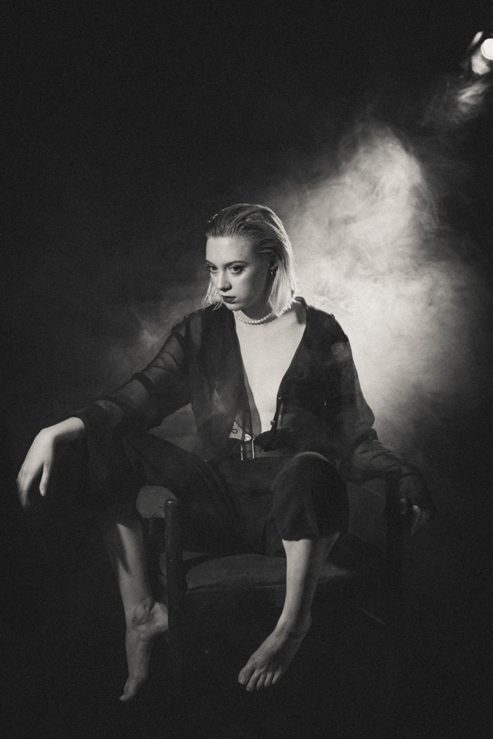 Dramatic portrait in chair with smoke effect and dark clothing.