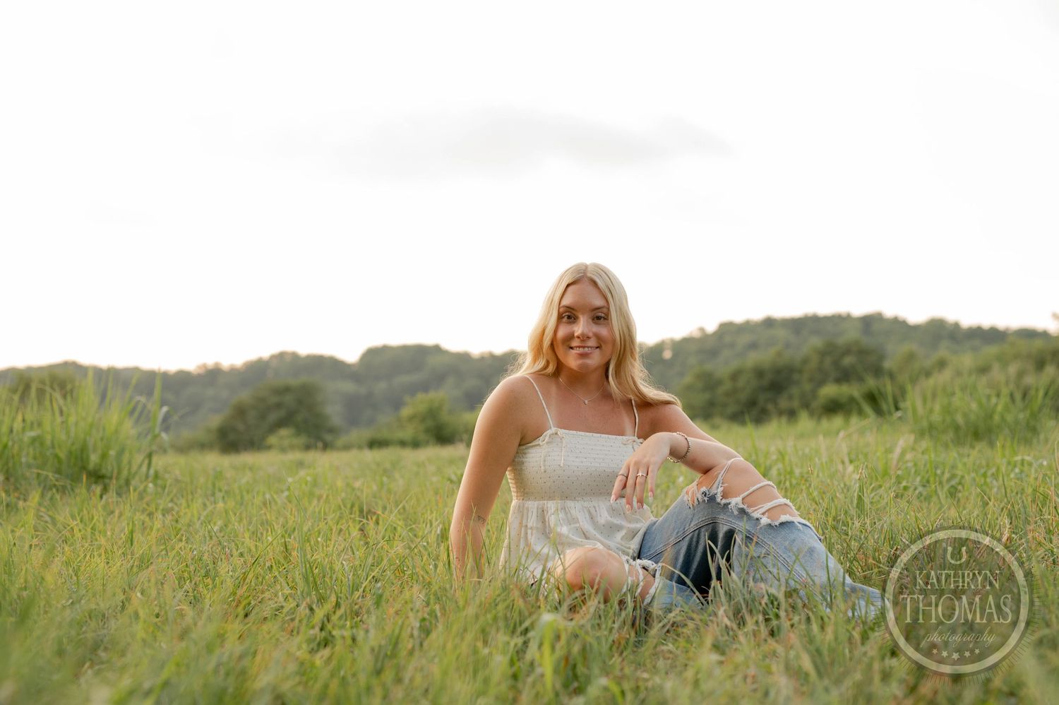 Relaxed outdoor portrait in a field with soft natural lighting and distressed denim.