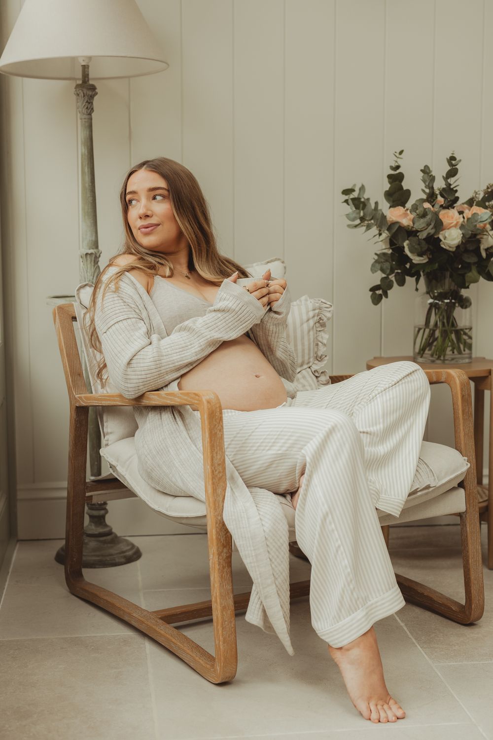 Maternity lifestyle photos in a cozy chair with white textured fabrics.