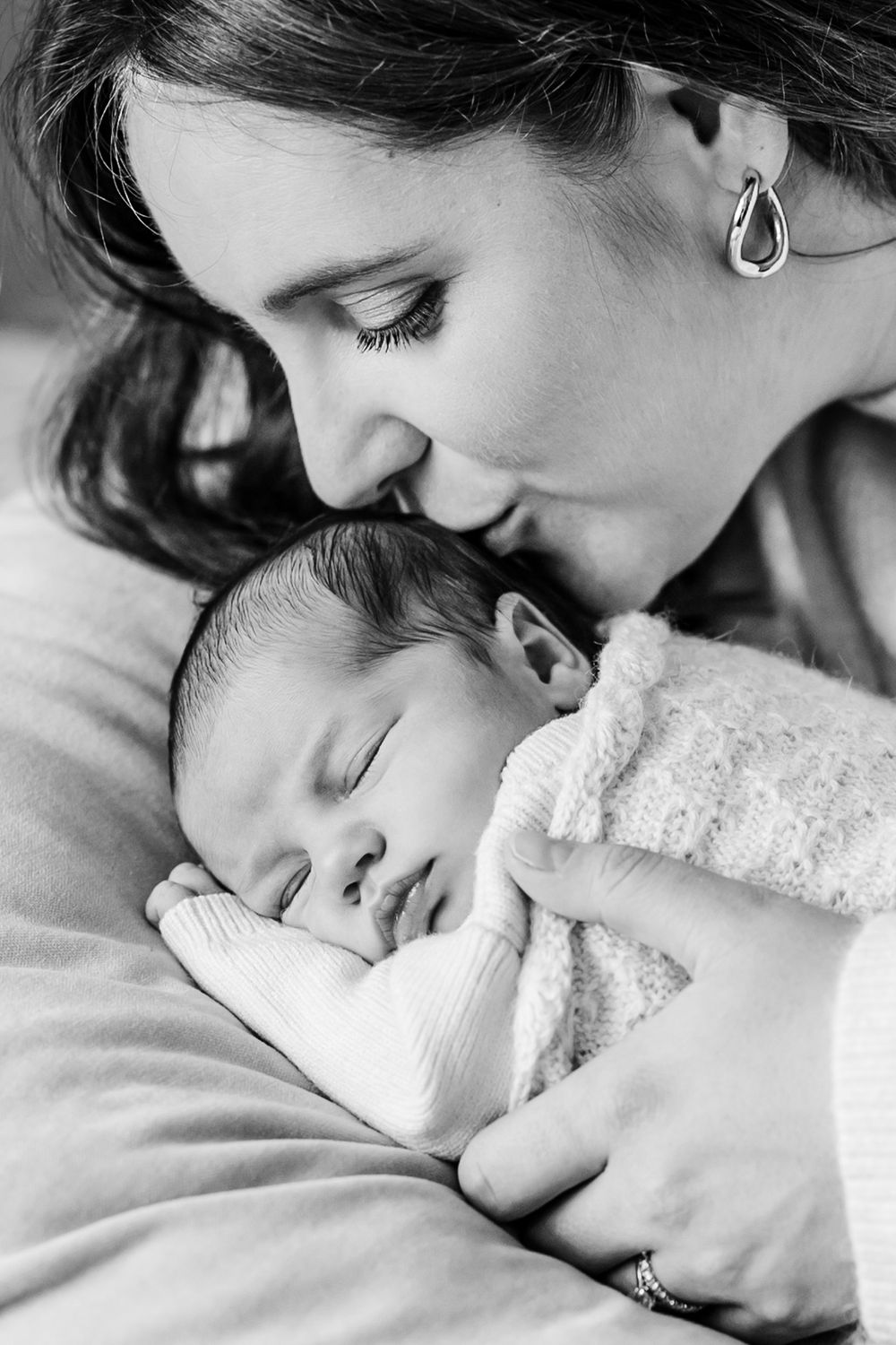 Intimate black and white newborn photography session with soft lighting.