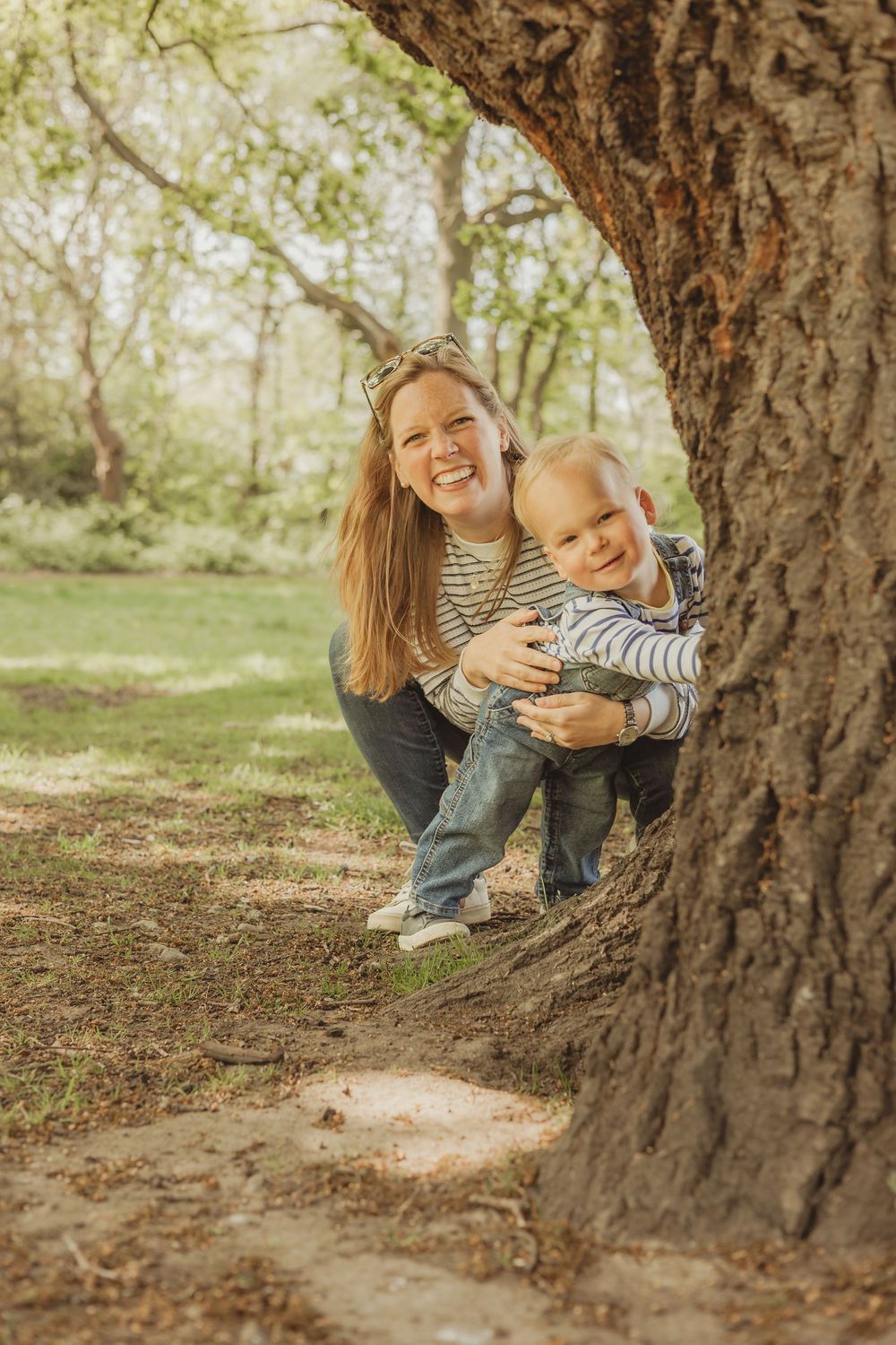 toddler and mum playing hide and seek behind a tree on Wandsworth common