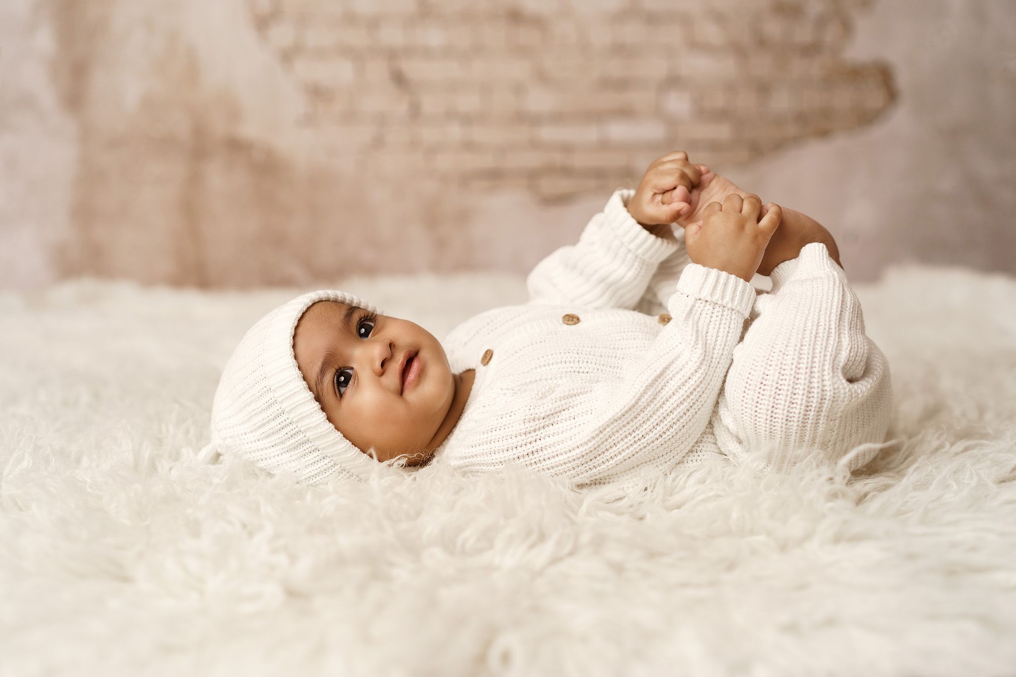 Happy Baby lying on white fluffy rug